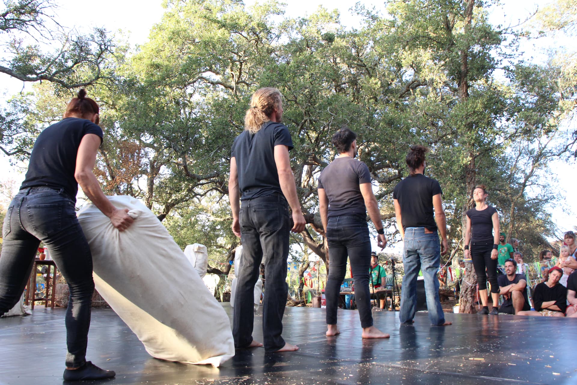 Artistas em cena no palco ao ar livre, com público entre sobreiros