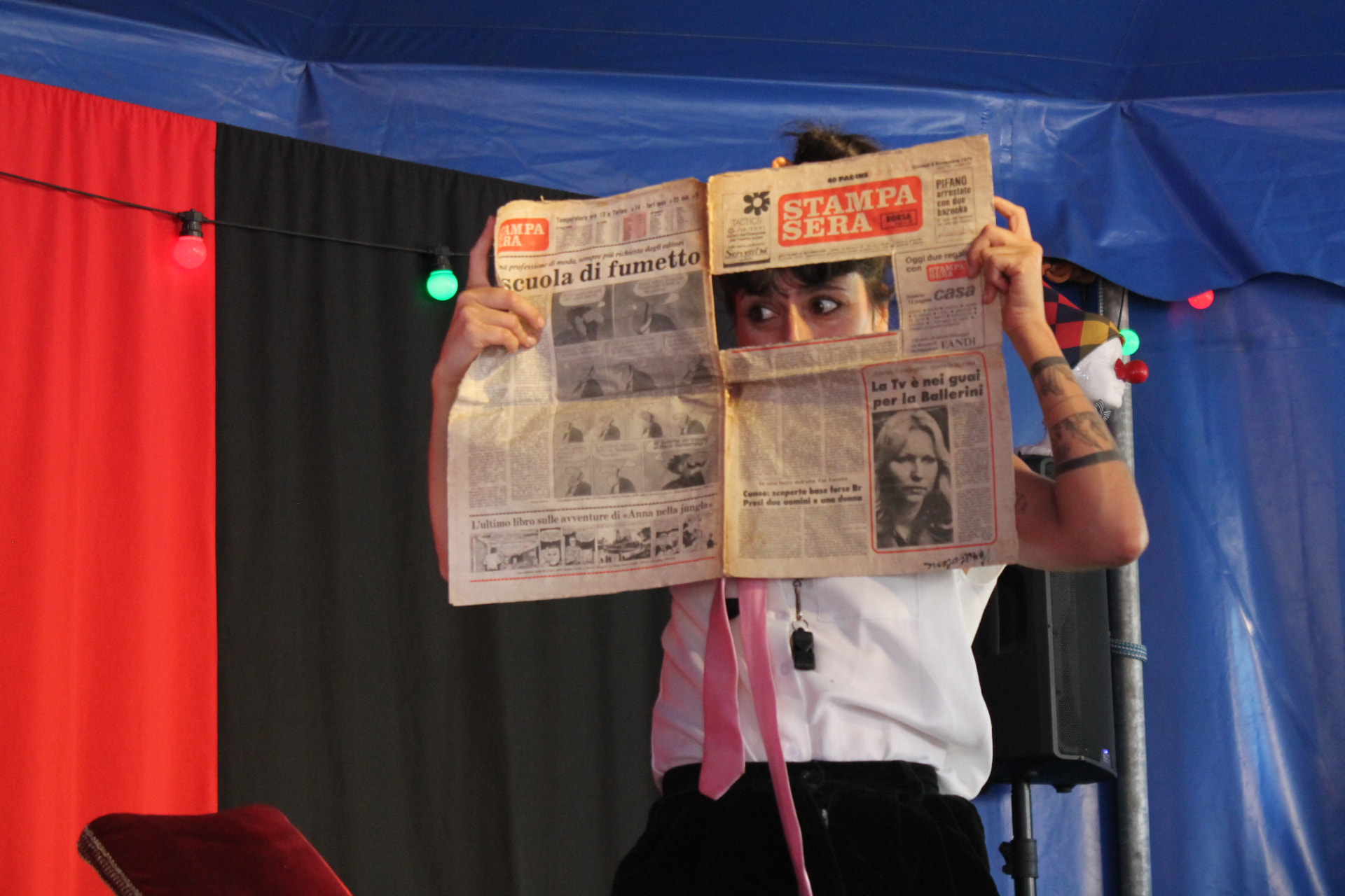 Artista a espreitar por trás de um jornal aberto numa tenda de circo