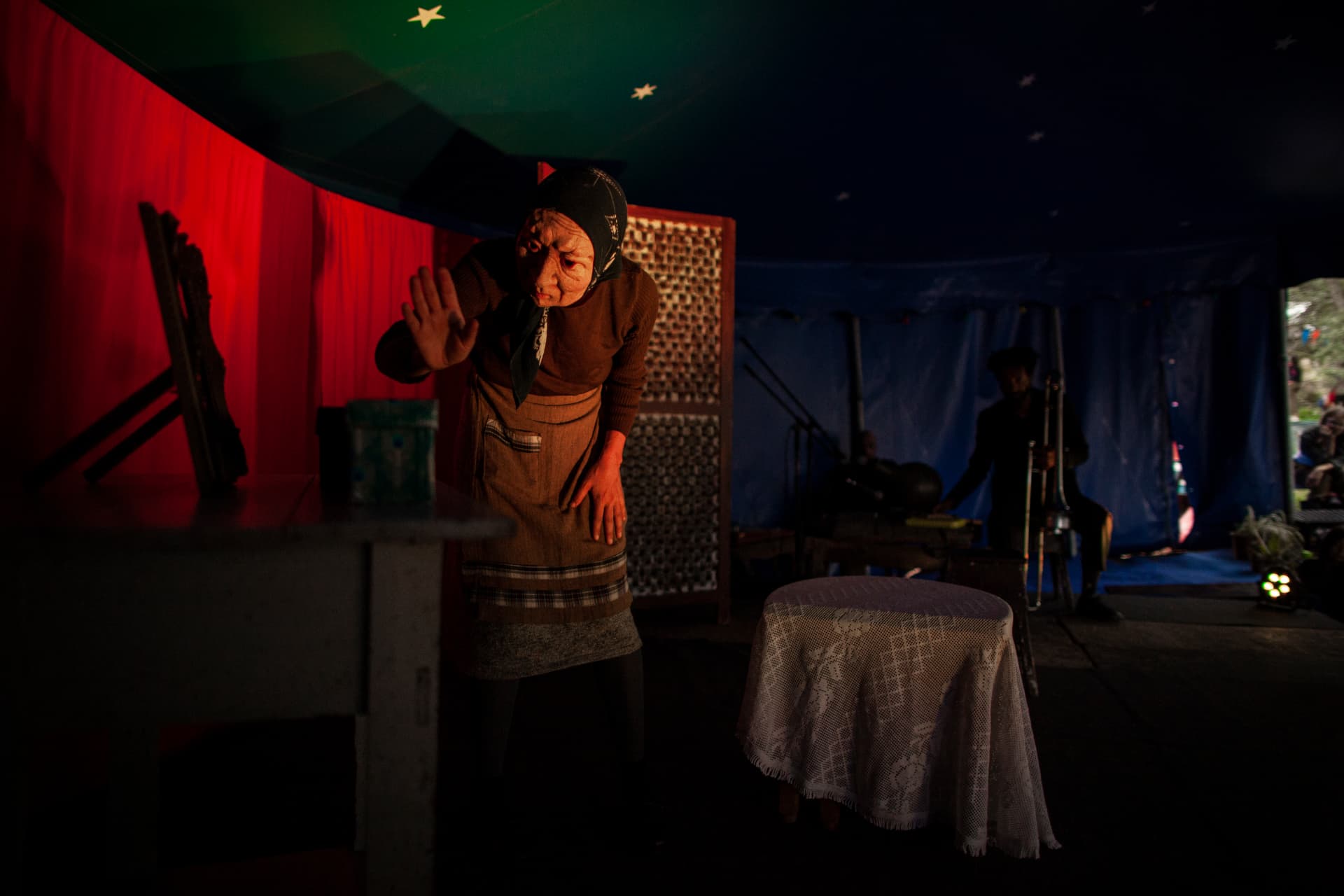 Atriz em cena numa tenda de circo com iluminação vermelha e azul
